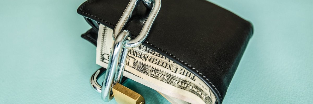 A wallet full of money is locked up with a chain and a padlock.