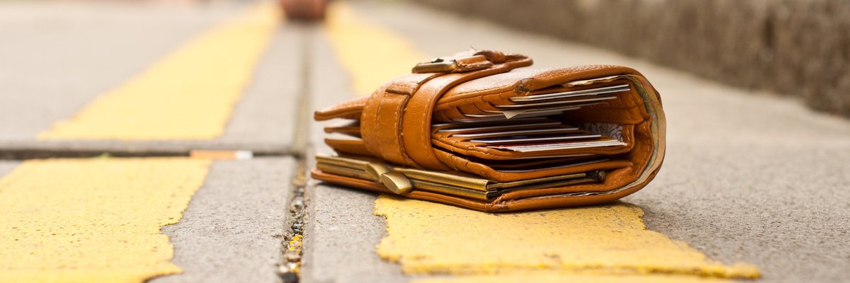A person walking away from the wallet they dropped on the ground and a thief's hand hovering over it.