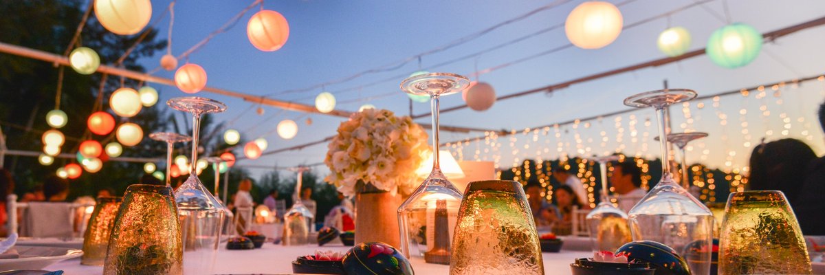Outdoor table settings at a wedding under paper lanterns