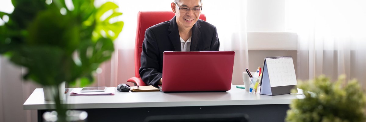 Well-dressed man smiling while using laptop.