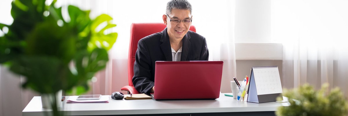 Well-dressed man smiling while using laptop.