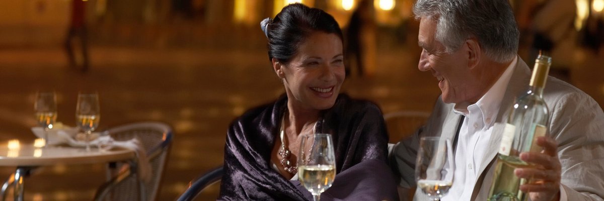 Well-dressed mature couple enjoying wine with a fancy meal.