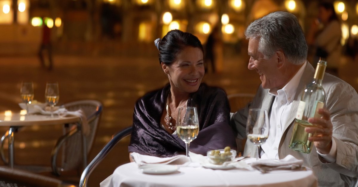 Well-dressed mature couple enjoying wine with a fancy meal.