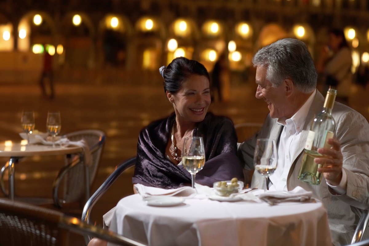 Well-dressed mature couple enjoying wine with a fancy meal.