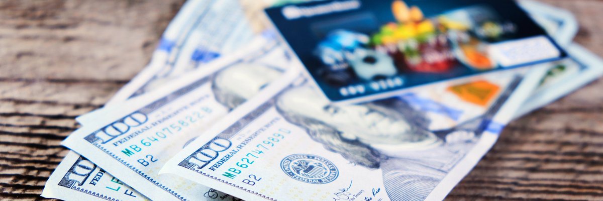 A travel credit card sits atop a stack of four hundred dollar bills.