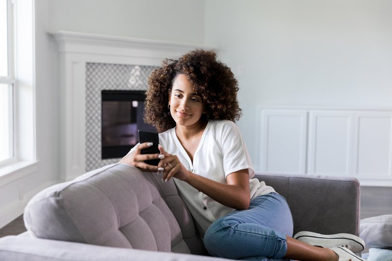 Woman Looking At Phone On Sofa