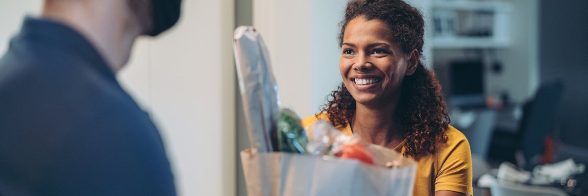 Woman accepting a delivery of groceries.