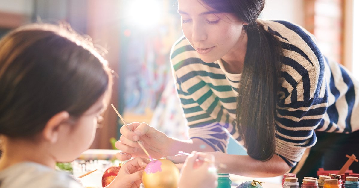 A woman and a young girl painting ornaments.