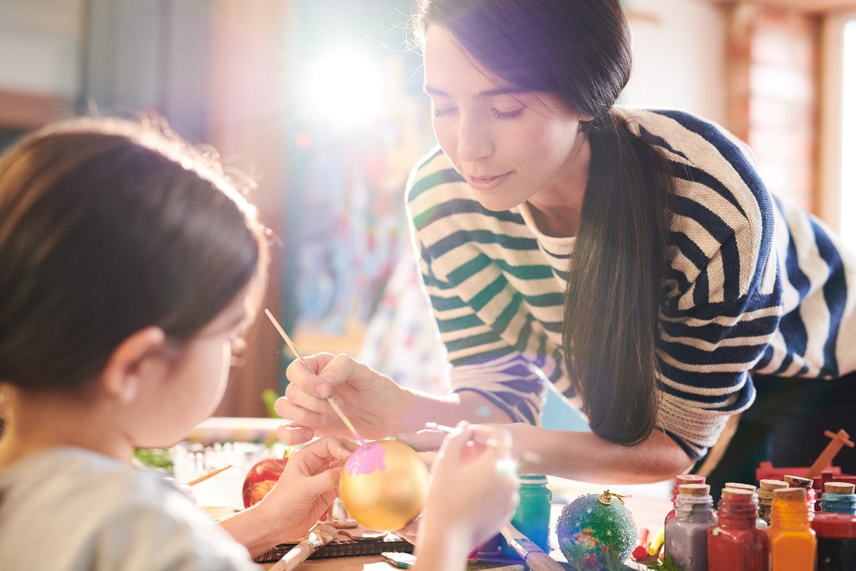 A woman and a young girl painting ornaments.