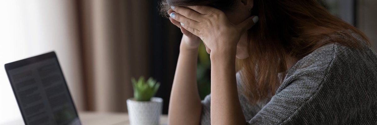 Woman appearing upset with head in her hands as she reads letter.