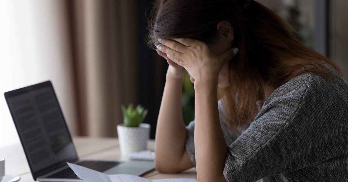 Woman appearing upset with head in her hands as she reads letter.