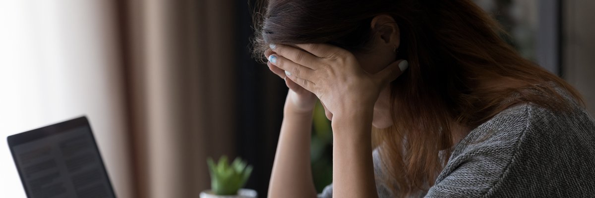 Woman appearing upset with head in her hands as she reads letter.