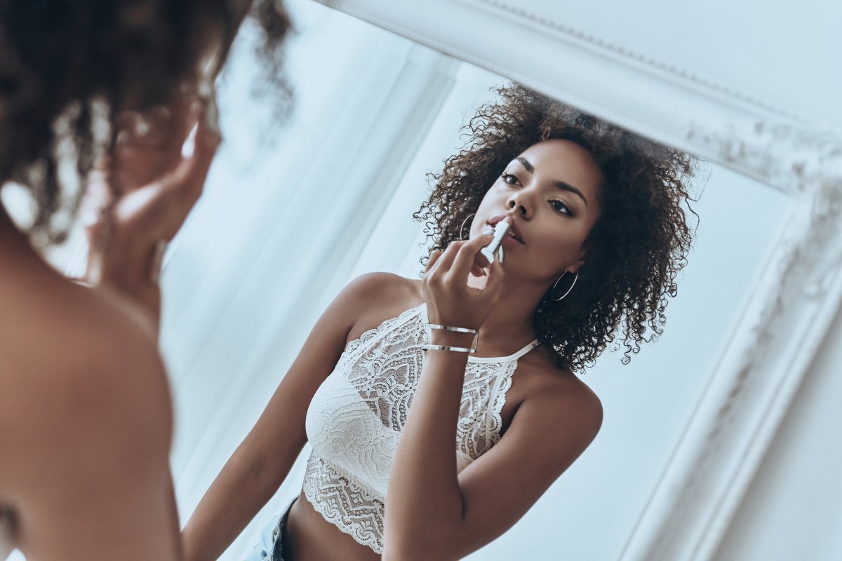 A woman applying lipstick in the mirror.