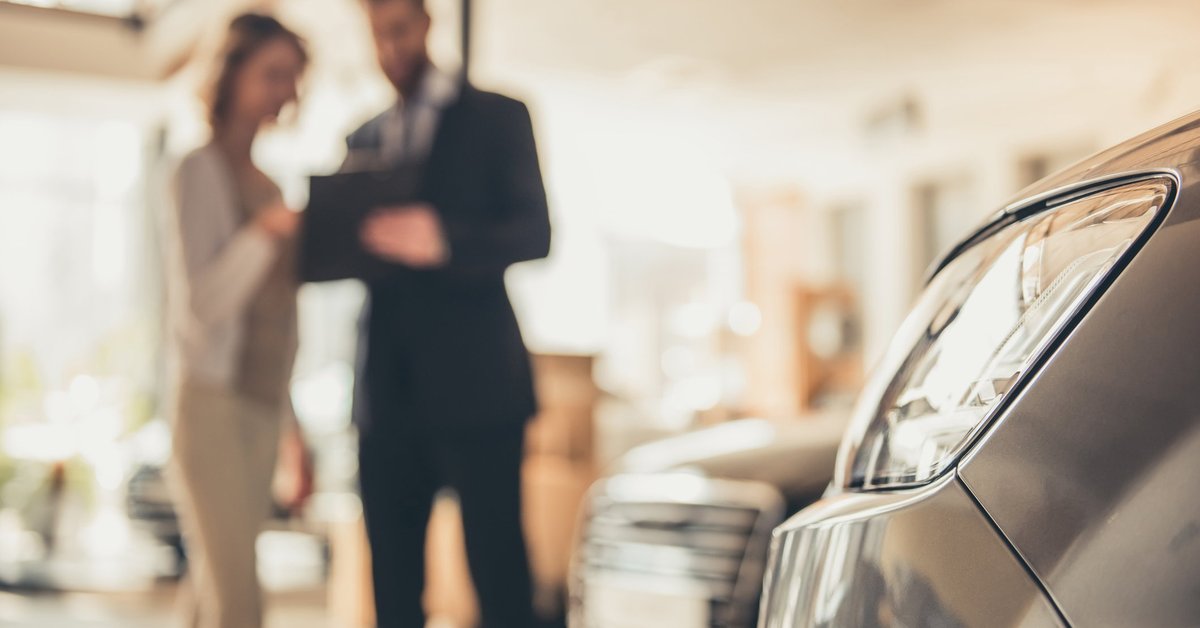 A woman speaking with a salesman about buying a car .
