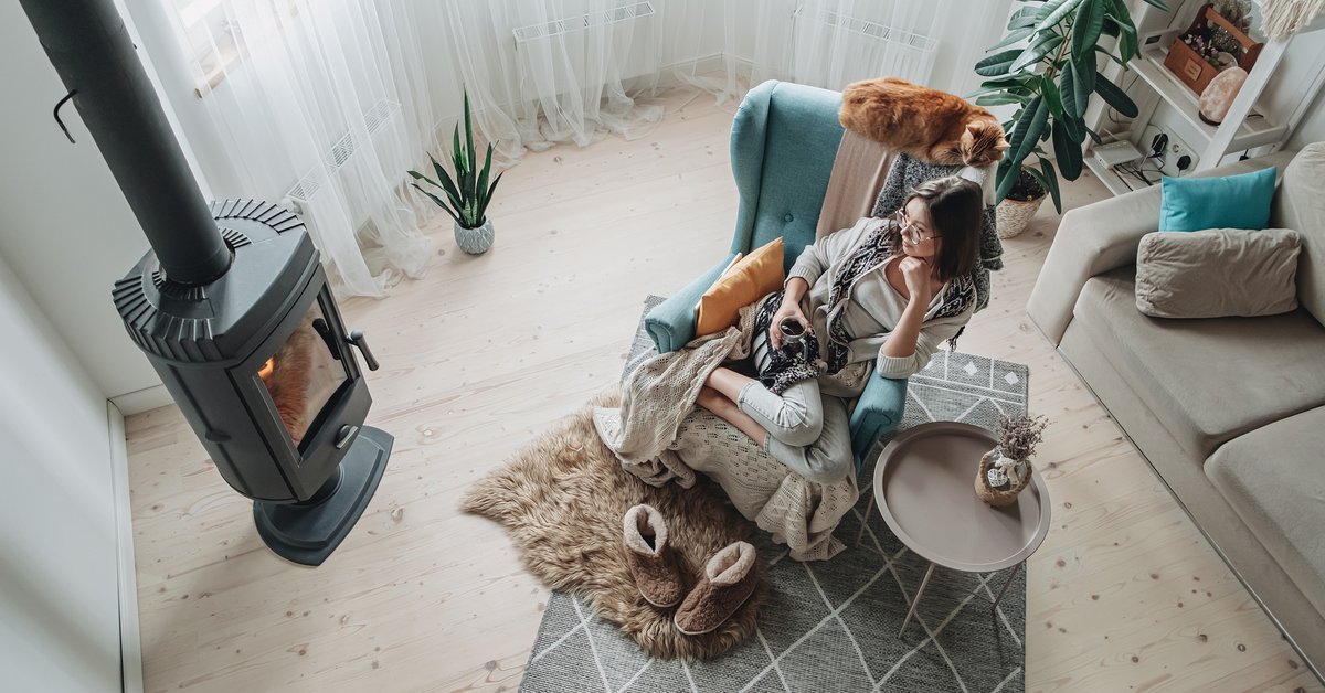 Woman cozy with blanket and slippers in front of fire.