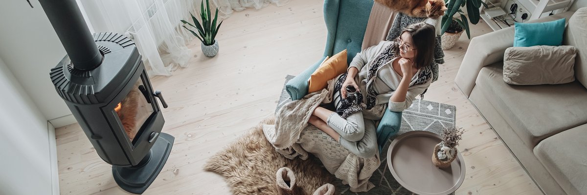 Woman cozy with blanket and slippers in front of fire.