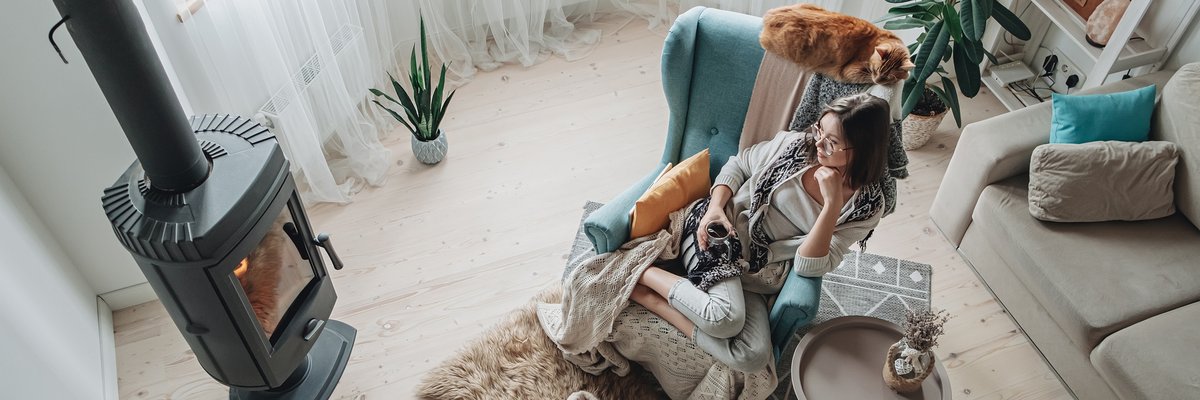 Woman cozy with blanket and slippers in front of fire.