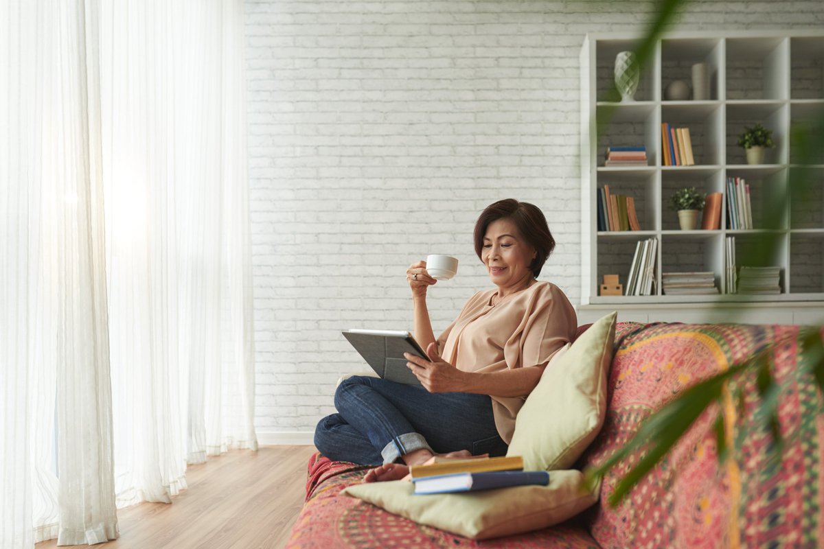 A woman drinking coffee on her couch.
