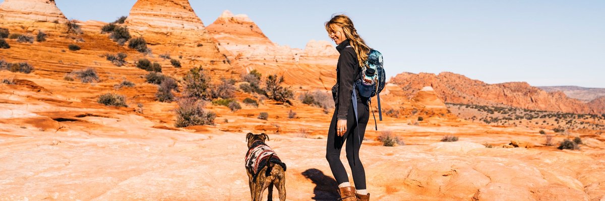 Woman hiking with dog in a southwest landscape.