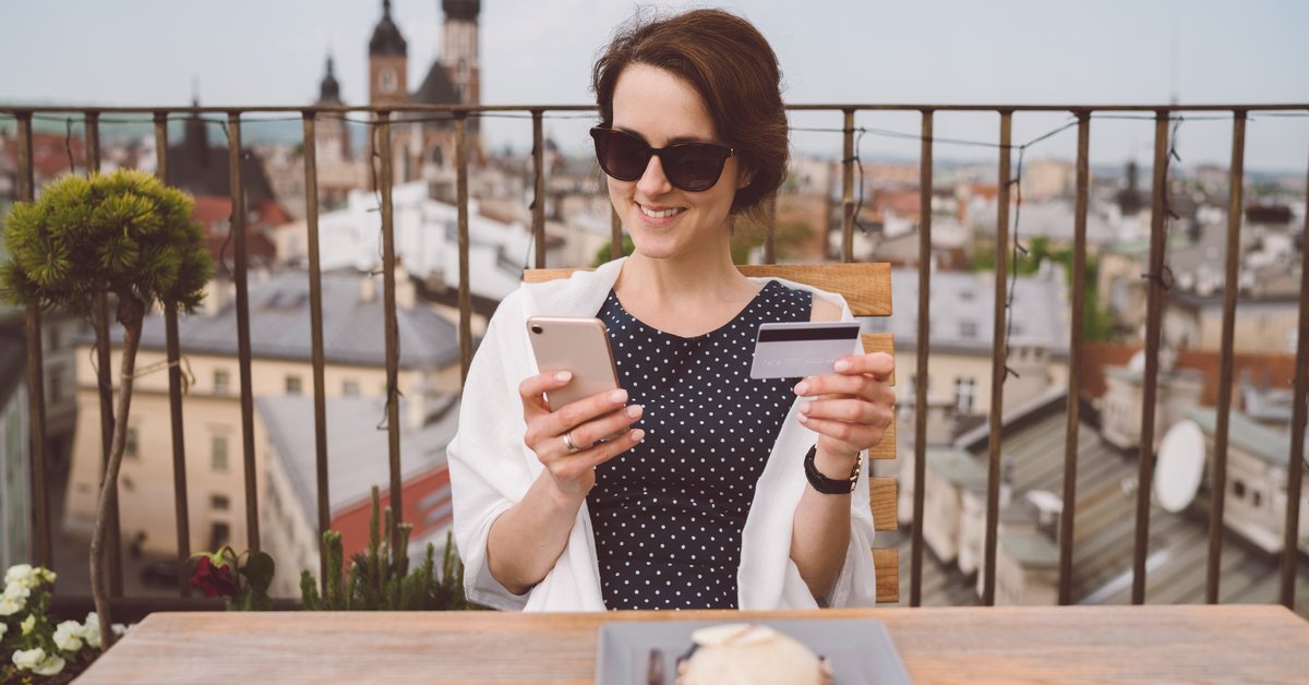 Woman holding her credit card and smiling while she dines in Europe