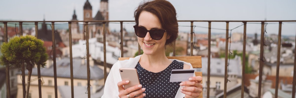 Woman holding her credit card and smiling while she dines in Europe