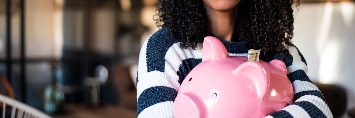 A smiling woman holding a piggy bank.