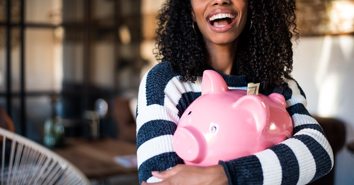 A smiling woman holding a piggy bank.