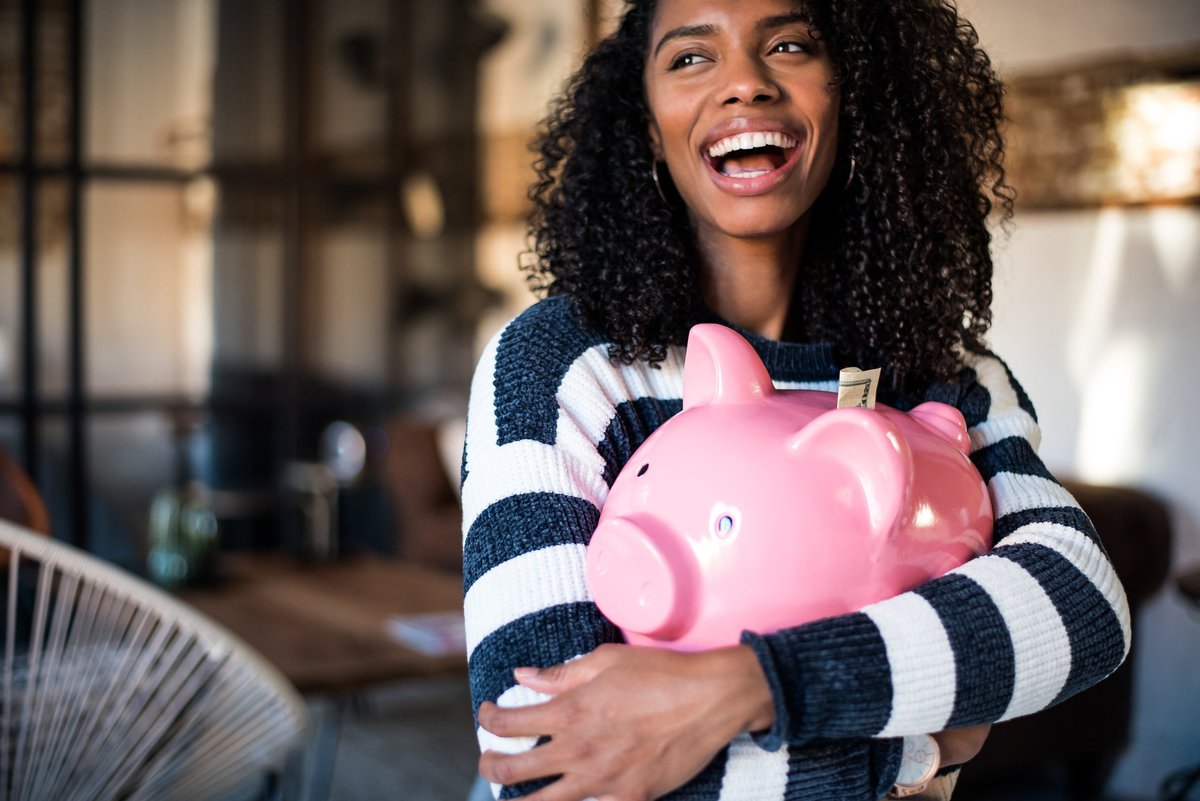 A smiling woman holding a piggy bank.