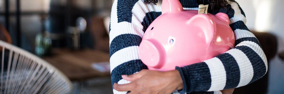A smiling woman holding a piggy bank.