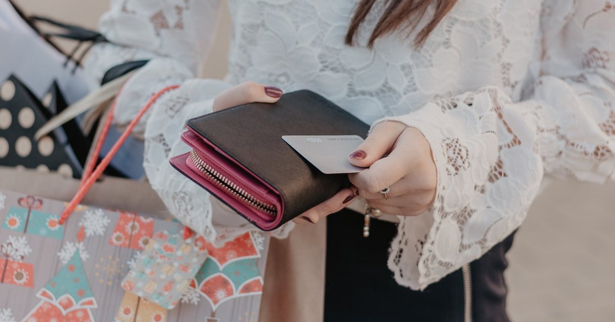 A woman holding shopping bags and a credit card.