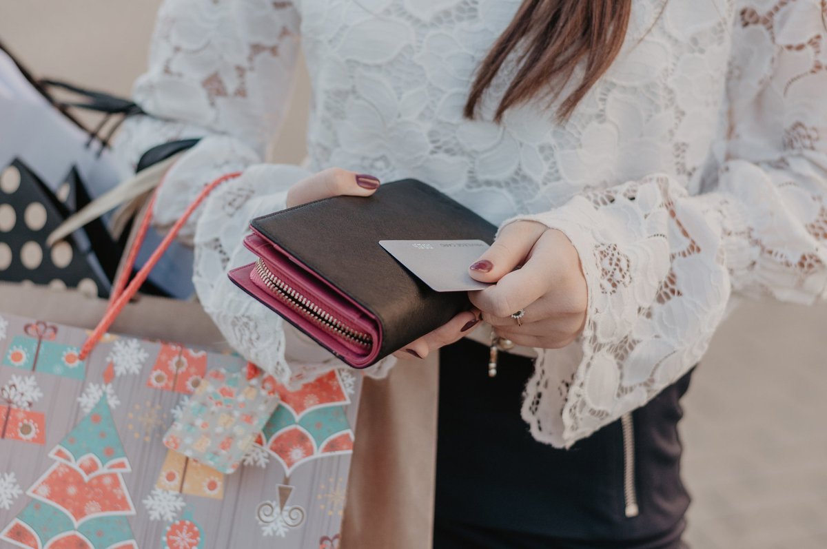 A woman holding shopping bags and a credit card.