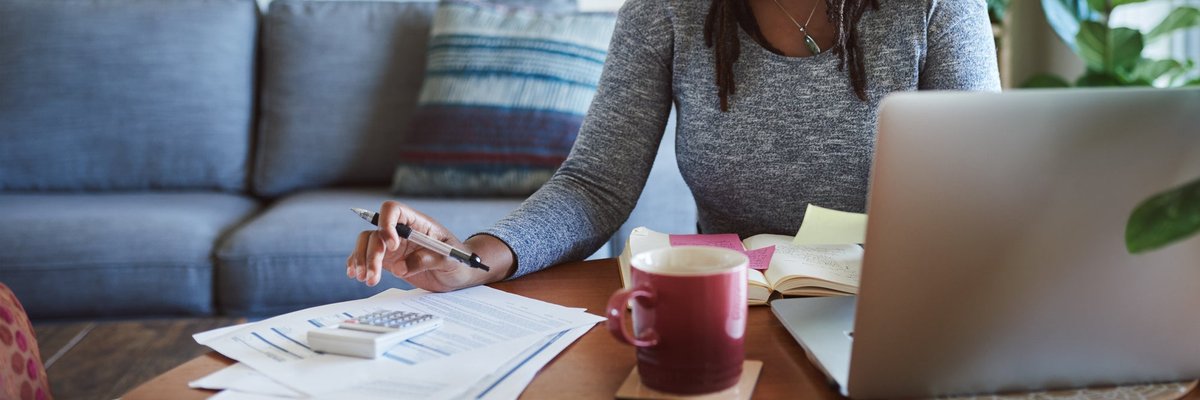 Woman making calculations as she uses her laptop.