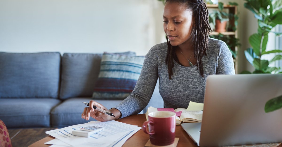 Woman making calculations as she uses her laptop.