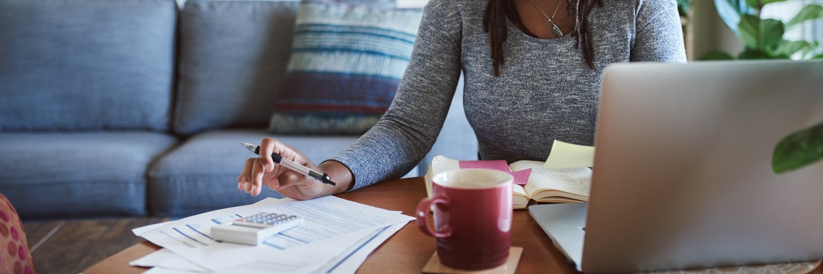 Woman making calculations as she uses her laptop.