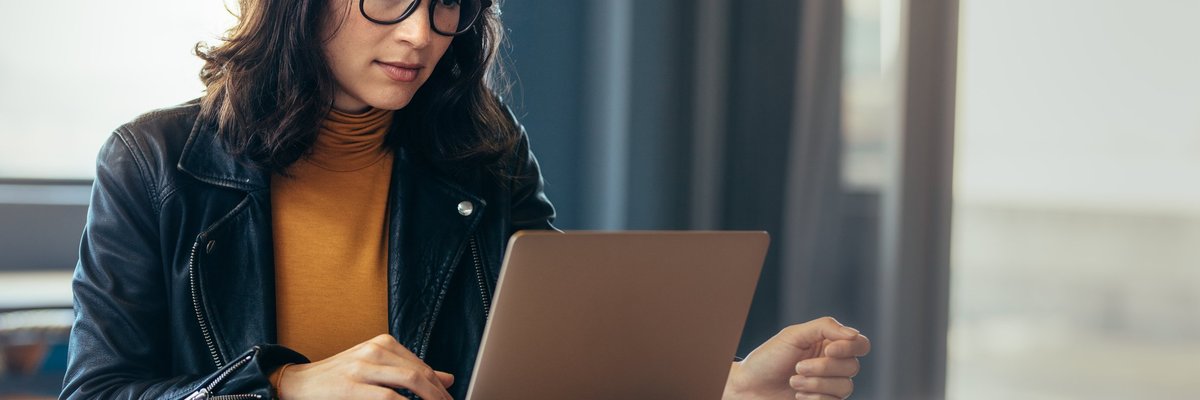 A woman sitting at a table with a laptop and papers in front of her.