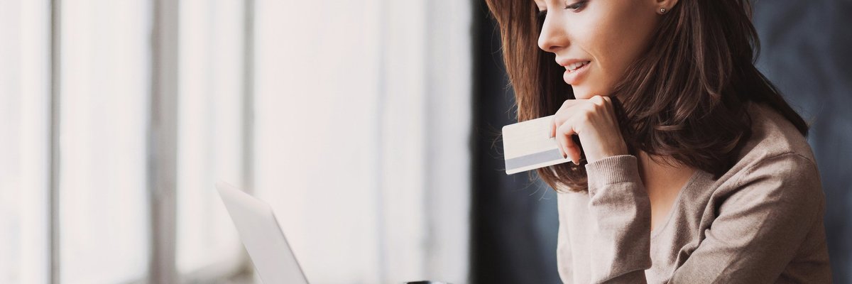 A woman using a laptop and holding a credit card.