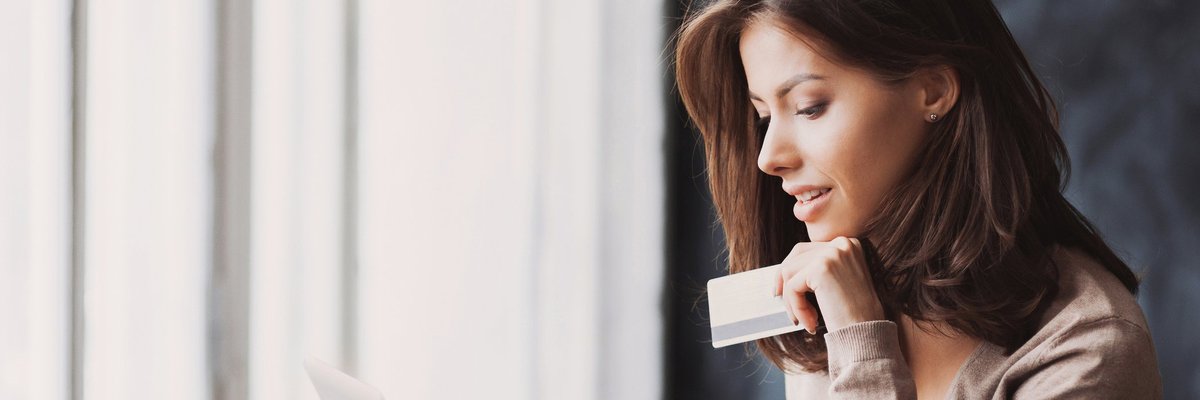 A woman using a laptop and holding a credit card.