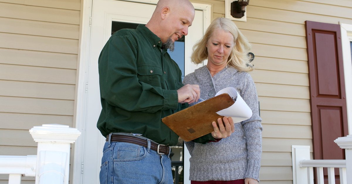 Woman on porch talking to man with clipboard.