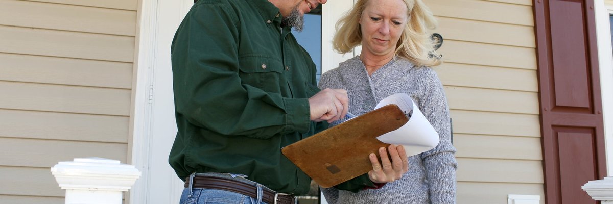 Woman on porch talking to man with clipboard.