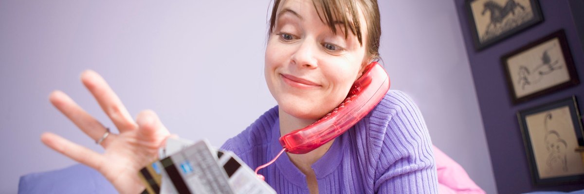 Woman on the phone and holding several credit cards in her free hand.