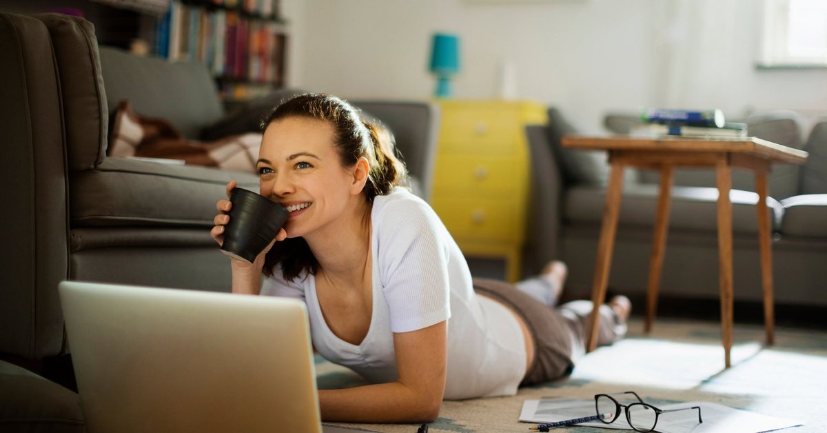 A woman pauses working on her personal finances to enjoy a cup of coffee.