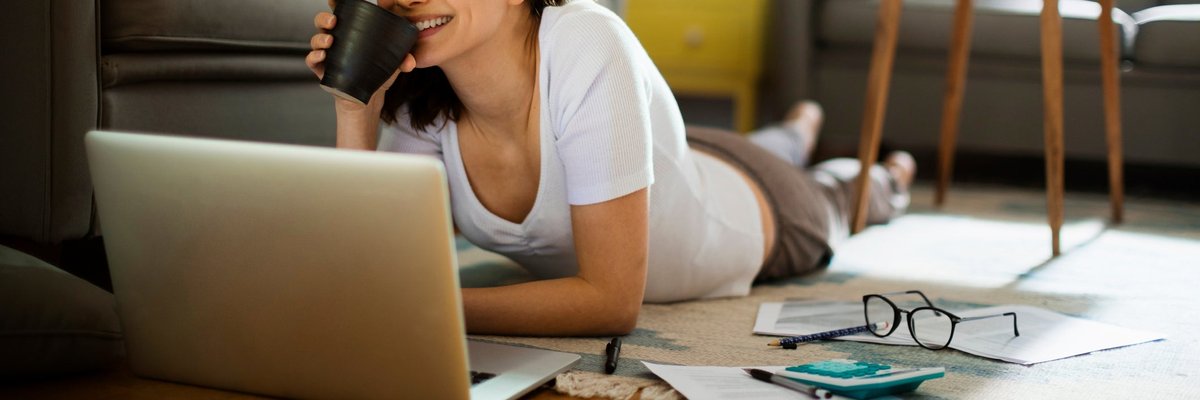 A woman pauses working on her personal finances to enjoy a cup of coffee.