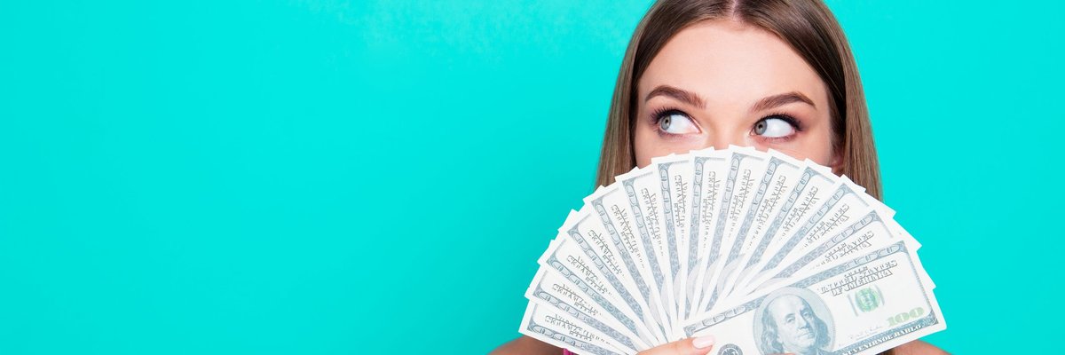 Woman peeking over a handful of money