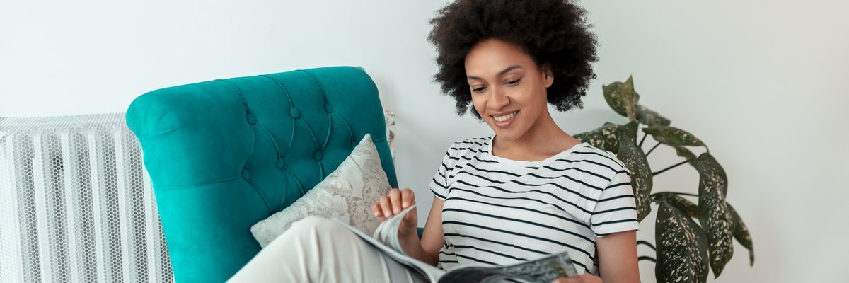 Woman reading magazine in a chair.