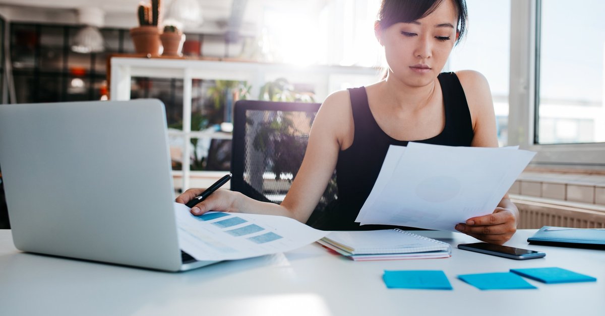 A woman reading papers at an office desk.