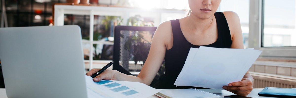 A woman reading papers at an office desk.