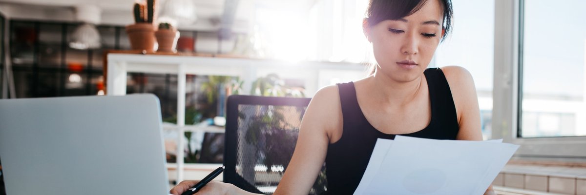 A woman reading papers at an office desk.