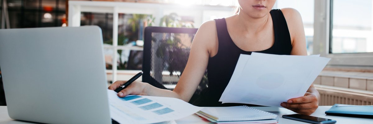 A woman reading papers at an office desk.