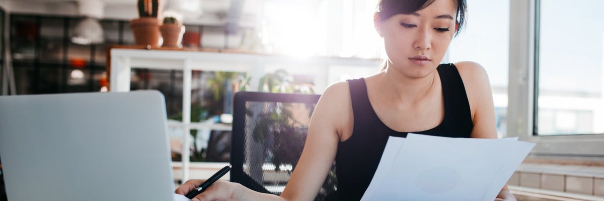 A woman reading papers at an office desk.