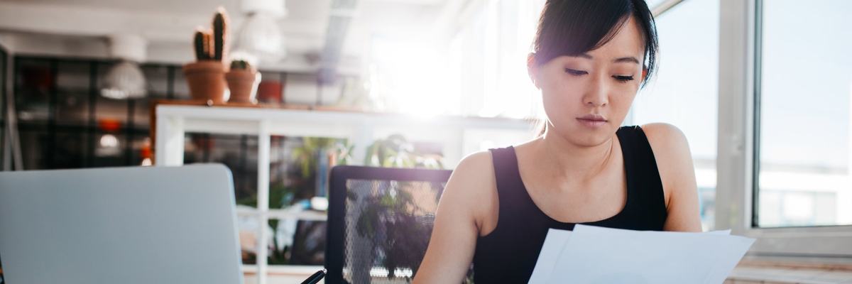 A woman reading papers at an office desk.